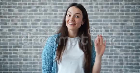一幅友好的女人挥舞着手看着镜头脸上洋溢着幸福的笑容视频的预览图
