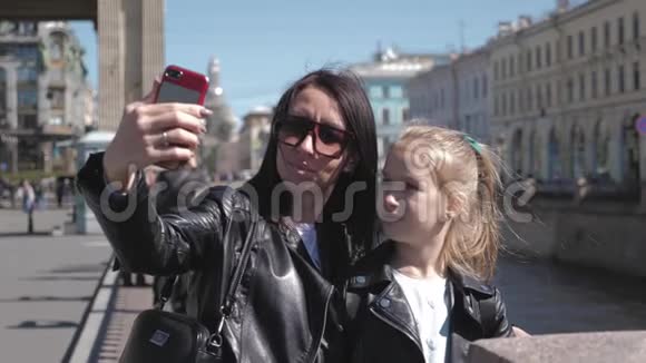 母女十几岁的孩子在城市的智能手机上自拍家庭旅游和旅游理念视频的预览图