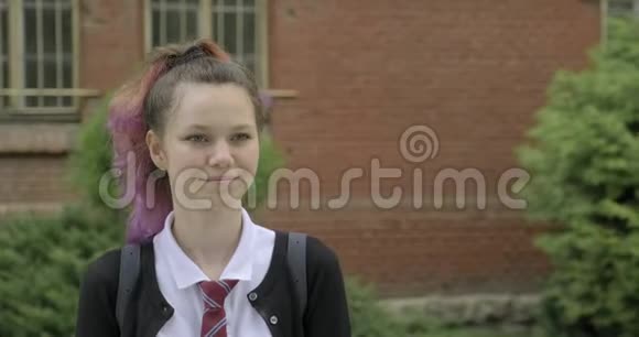 穿制服带背包的少女在学校大楼附近行走视频的预览图