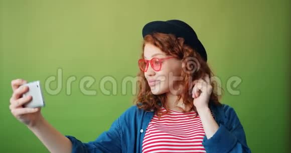 可爱的红头发女孩自拍与智能手机相机摆姿势的肖像视频的预览图