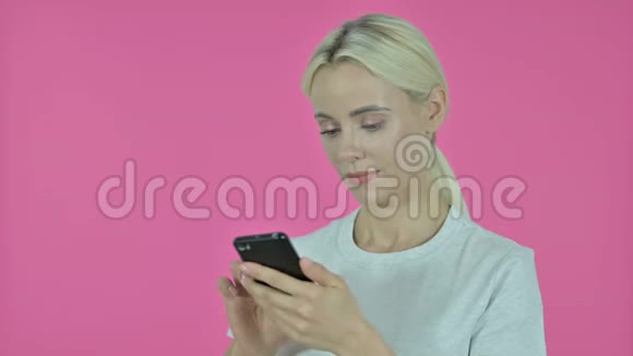 年轻女子在智能手机粉红背景下取得成功视频的预览图