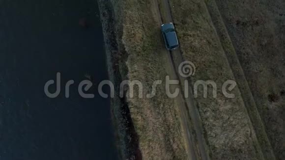 汽车骑在悬崖边沿蓝色海面顶部的鸟瞰从无人机沿海岸行驶的黑色越野车苏夫视频的预览图