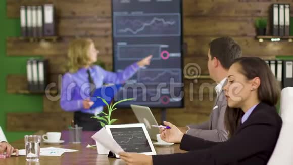商业女性在一次金融会议上指出电视屏幕上的图表视频的预览图