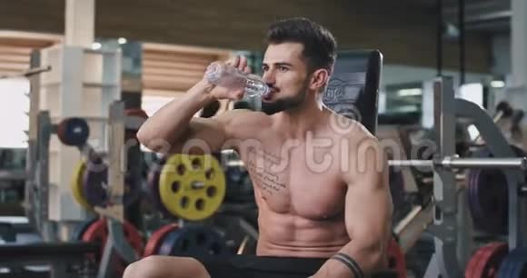 一个性感的肌肉男在完成了非常艰苦的锻炼后正在喝水他看起来汗流浃背疲惫不堪视频的预览图