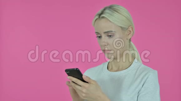 因智能手机粉色背景的丢失而震惊年轻女性视频的预览图