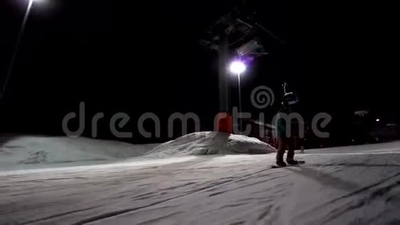 滑雪板的慢速运动从脸上被骑到镜头前滑雪道在夜间被点燃滑雪道视频的预览图