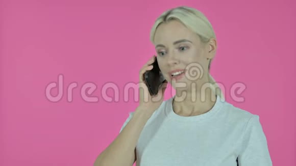 粉红背景下讲智能手机的年轻女性视频的预览图