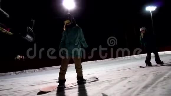 女滑雪者在灯光前的夜空下缓慢运动视频的预览图