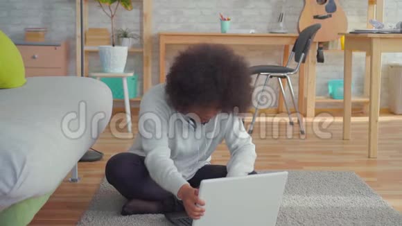 美丽的非裔美国女人她留着非洲发型坐在地板上手提电脑了解了温慢莫的故事视频的预览图