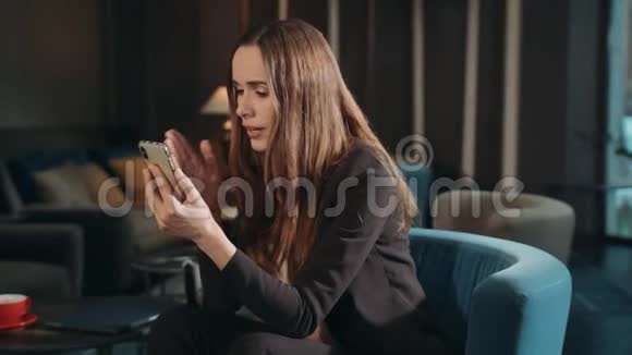 愤怒的女商人在酒店休息室用手机在线打视频电话视频的预览图