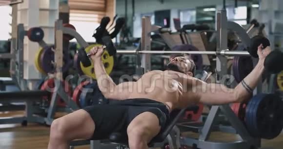 一个男人用他的粪钟重量做繁重的锻炼他看起来很英俊集中精力锻炼腹肌视频的预览图