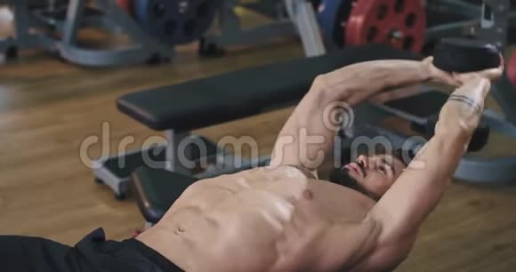 肌肉发达的大个子在健身的时候看起来很集中他在一个明亮的健身房里看起来很整洁干净视频的预览图