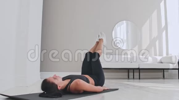 在家训练女运动员适合女性运动员在白色公寓里躺在地板上做脚趾接触单臂运动视频的预览图
