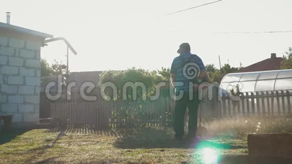 男人用修剪器在他的花园院子里割草慢动作男子用手动割草机割草视频的预览图