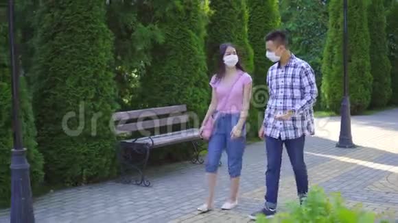 两个戴着医用口罩的亚洲青年学生走在大街上交谈视频的预览图