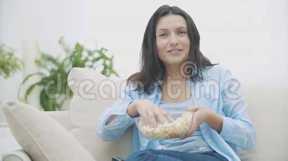 慢点一个可爱的女人一边吃着爆米花一边惊讶地看电视好吃好吃4K视频的预览图