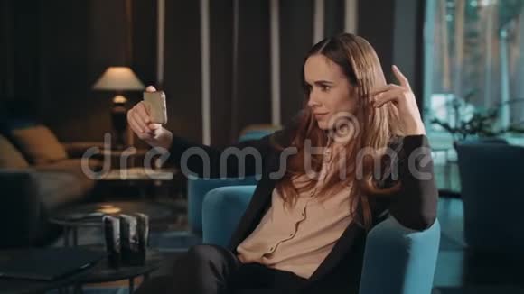 商务女性在椅子休息室用智能手机做手机自拍视频的预览图