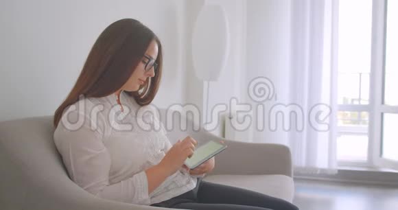 特写侧景照片年轻的白种人妇女戴眼镜使用平板电脑并显示绿色屏幕相机视频的预览图