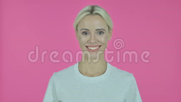 微笑的年轻女子看着镜头粉红的背景视频的预览图