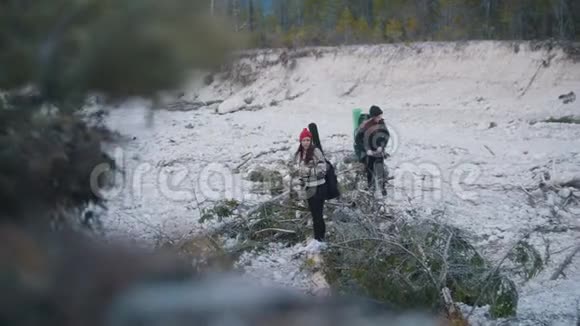 两个年轻的女人站在岩石路上背着背包和吉他站在森林和山脉的背景上视频的预览图