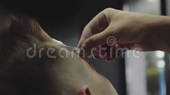 专业理发师用开刀剃须刀剃毛人的太阳穴有魅力的男性正在理发视频的预览图
