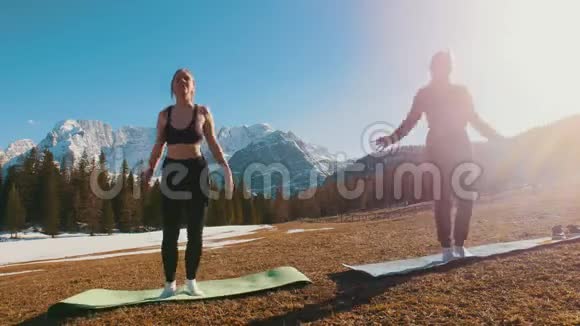 两个年轻的女人在森林和山脉的背景下伸展着瑜伽垫视频的预览图