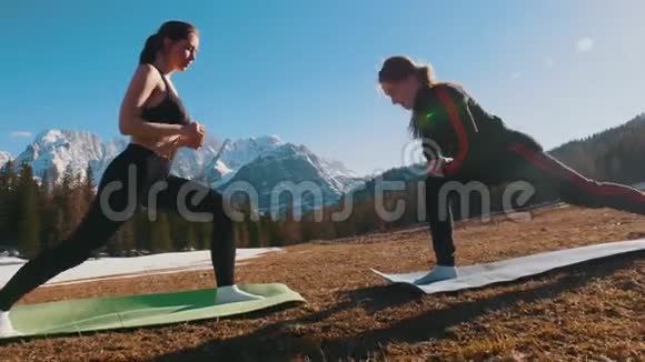 两个年轻的女人在森林和山脉的背景下伸展双腿视频的预览图