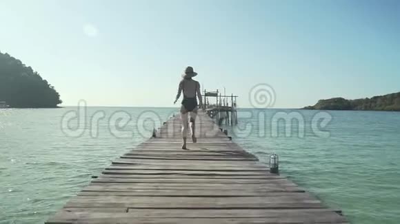 女人在热带海滩的木制码头上奔跑视频的预览图
