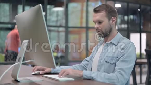 年轻男子在电脑工作时竖起大拇指视频的预览图