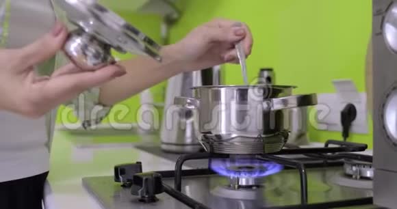 女人在厨房的煤气炉上用小金属锅做饭视频的预览图