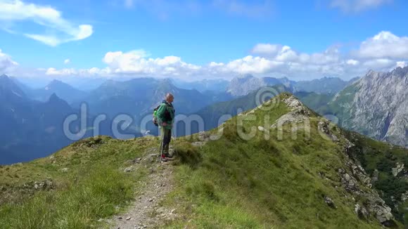 在阳光明媚的夏日里快乐的徒步旅行者在山顶上漫步美丽的山景视频的预览图