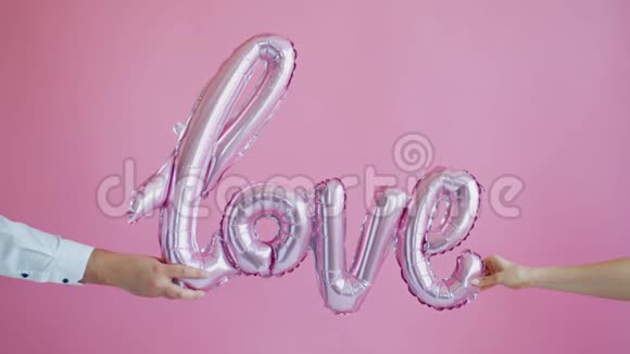 特写男女双手在粉色背景上握着爱的话语视频的预览图