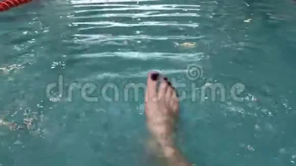 女在酒店的游泳池里双脚溅起水花视频的预览图