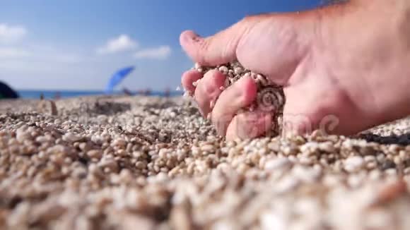 从海边的沙滩上拿沙砾的人手视频的预览图