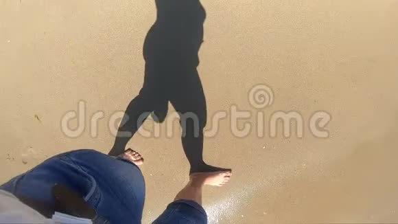 在阳光明媚的日子里女孩走在海边波浪在沙滩上翻滚视频的预览图