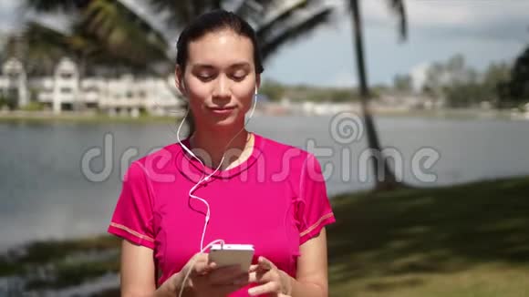 湖畔智能手机上听音乐的休闲女性视频的预览图