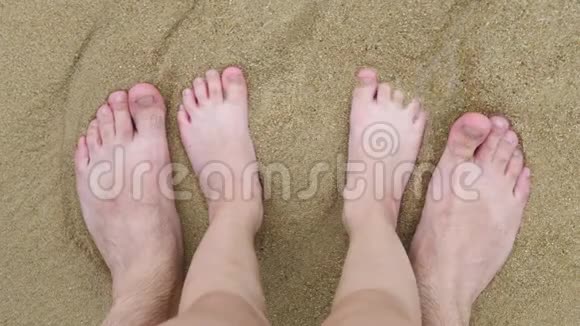 父亲和女儿的双腿在海浪拍打的沙滩上视频的预览图