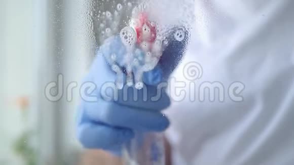 用蓝色手套用喷射液体清洁窗户视频的预览图