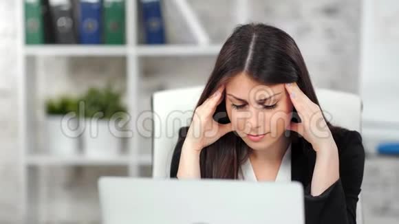 疲惫的年轻女商人看着办公室媒体特写的笔记本电脑屏幕视频的预览图