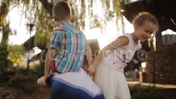 父亲抚养两个孩子一个女儿和一个儿子日落时在公园玩得开心的一家人视频的预览图