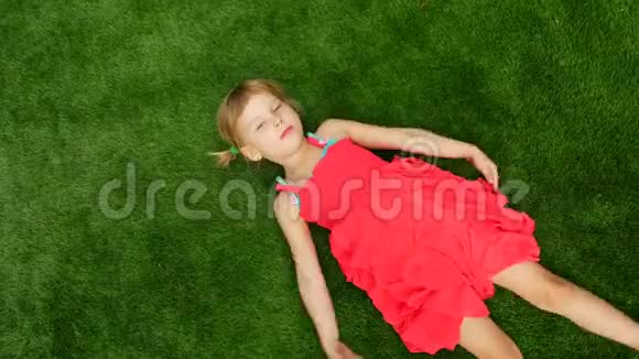 小女孩躺在绿草上俯视着孩子使天使像在雪地里视频的预览图