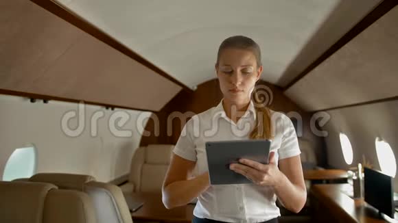 女商人在空中私人飞机上用数字垫上网视频的预览图
