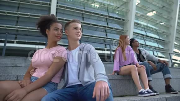 两对多种族的青少年坐在户外的楼梯上浪漫的年轻人视频的预览图