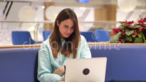 一个穿着运动衫的年轻女子开发了一个应用程序她点击一台笔记本电脑并测试它4k视频的预览图