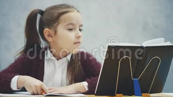 聪明细心的女学生坐在桌子旁做作业在这篇文章中练习看起来视频的预览图