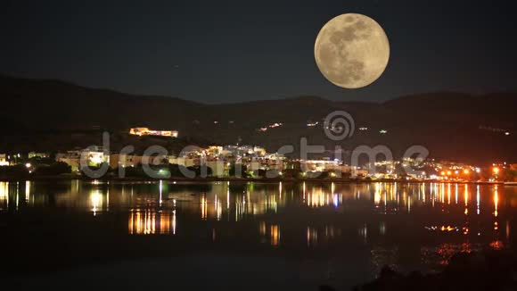满月在村庄上方升起反映在水面上希腊视频的预览图