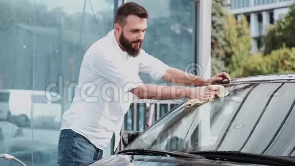 有胡子的男人在洗车场用布洗车视频的预览图