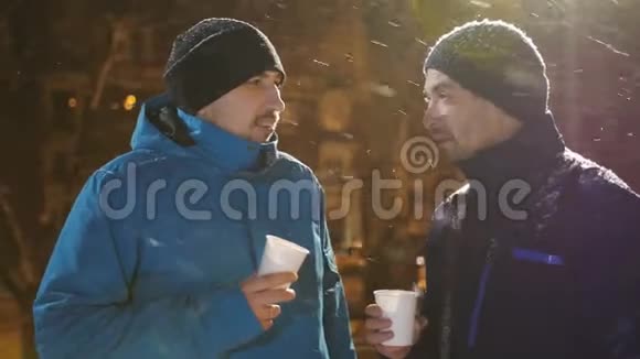 两个朋友在雪地下冬天在街上聊天喝咖啡视频的预览图