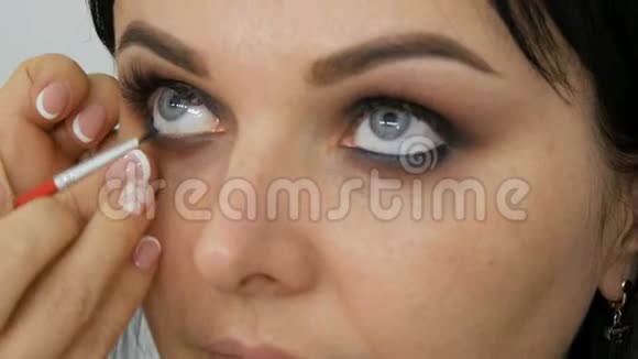 专业造型师化妆师将化妆应用于美丽年轻女性的眼睛眼线化妆烟熏眼视频的预览图