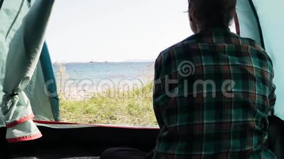 一个年轻的女旅行者坐在她的旅游帐篷里视频的预览图